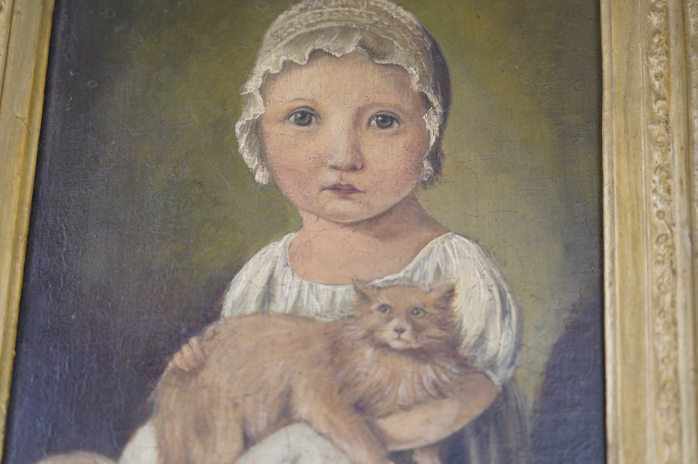 Early 19th naive School, oil on board, Study of a young girl with a cat, 24 x 20cm, ornate gilt frame. Condition - fair